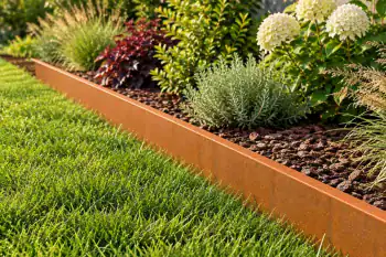 Bordura da giardino in acciaio Corten che separa il prato da un'aiuola fiorita con graminacee ornamentali