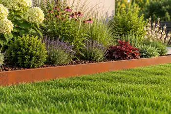 Bordura da giardino in acciaio Corten alta 15 cm che separa il prato dall'aiuola con graminacee ornamentali